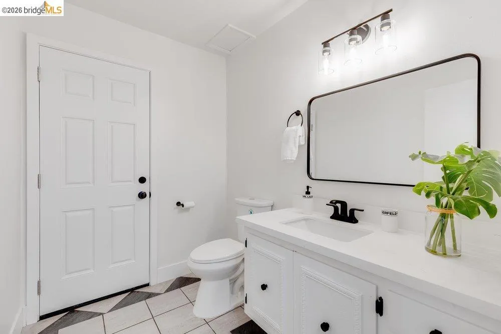 Modern bathroom featuring a white vanity with integrated sink, matte black hardware, and an overhead three-light fixture