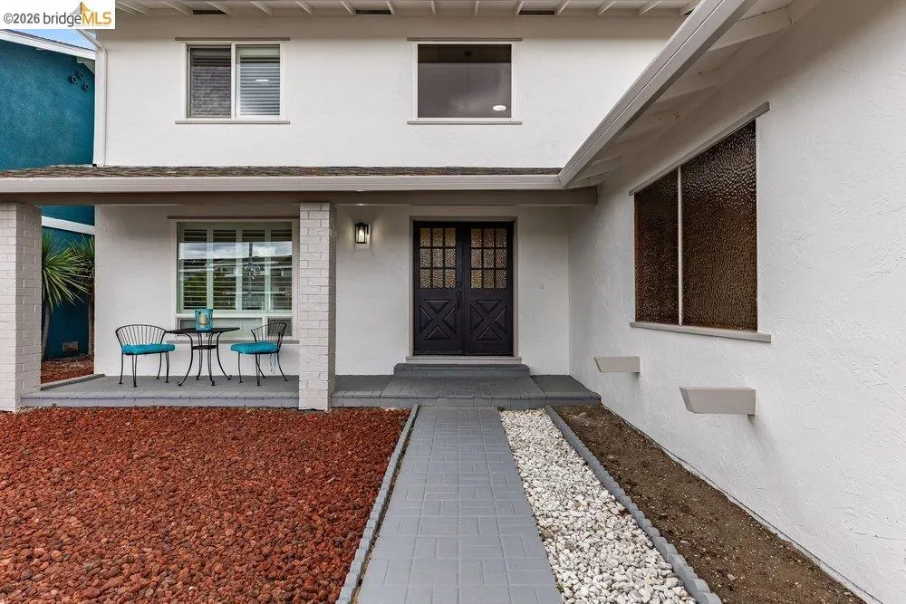 White stucco exterior with a covered porch featuring brick columns