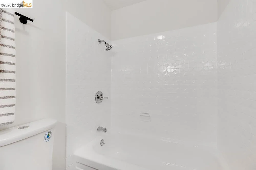White bathtub with chrome fixtures and embossed tile surround