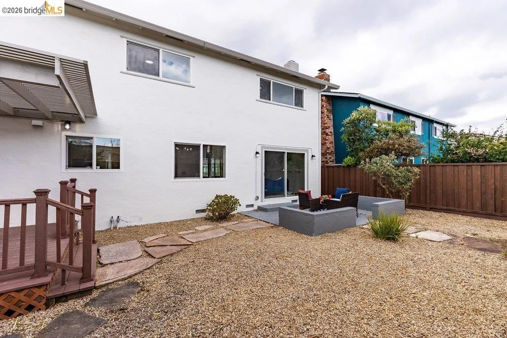 Expansive backyard featuring a gravel landscape, stone paver pathway, and a patio area with built-in planters