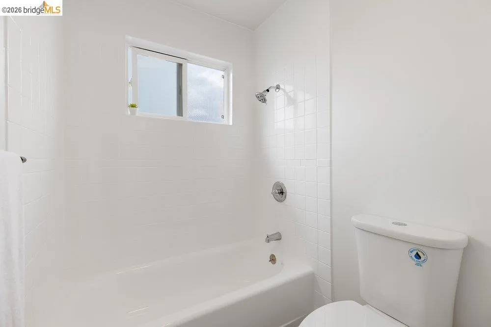 White-tiled bath and shower combination with a sliding window