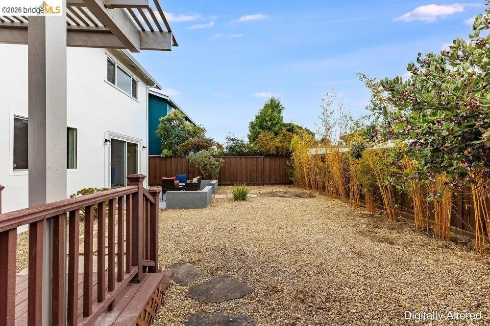 Spacious backyard featuring a gravel-covered surface, a concrete patio area, and a surrounding privacy fence