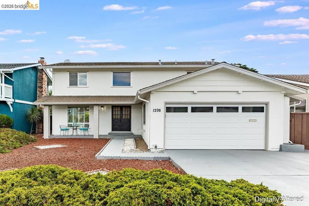 Two-story residence featuring a white stucco exterior and a covered front porch entry
