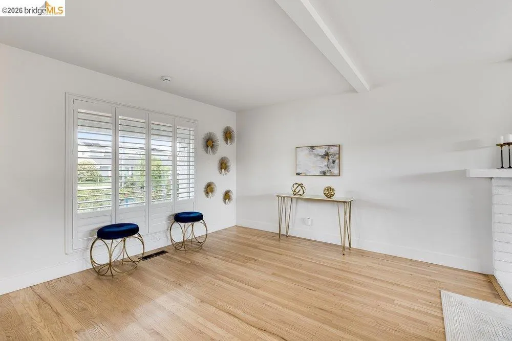 Hardwood flooring complements the bright white walls and ceiling beam