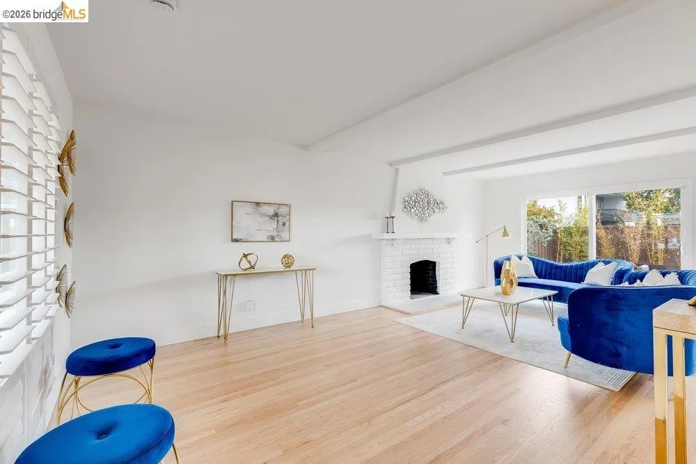Living space featuring wood-finish flooring, white walls, and exposed ceiling beams