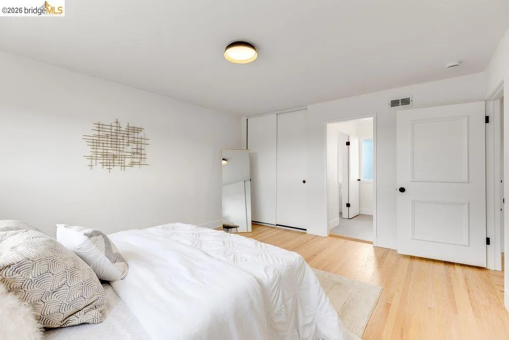 Bedroom with light wood-finish flooring, white walls, and a contemporary flush-mount ceiling light