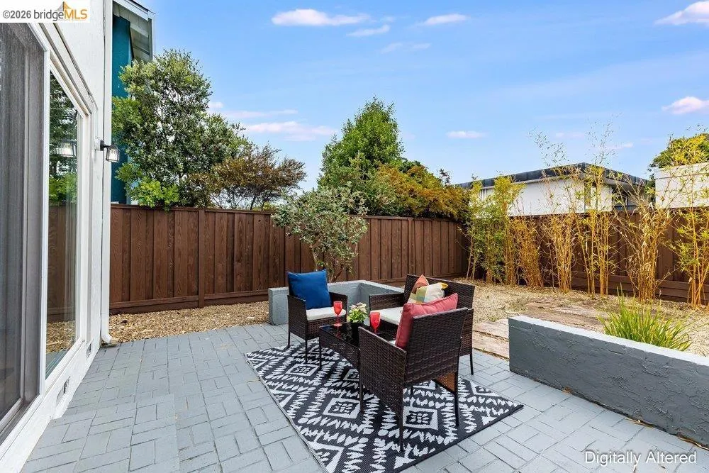 Paved patio area featuring gray pavers, a perimeter privacy fence, and integrated planter boxes