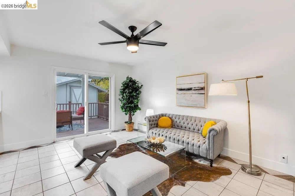 Bright living area with white tile flooring and a black ceiling fan