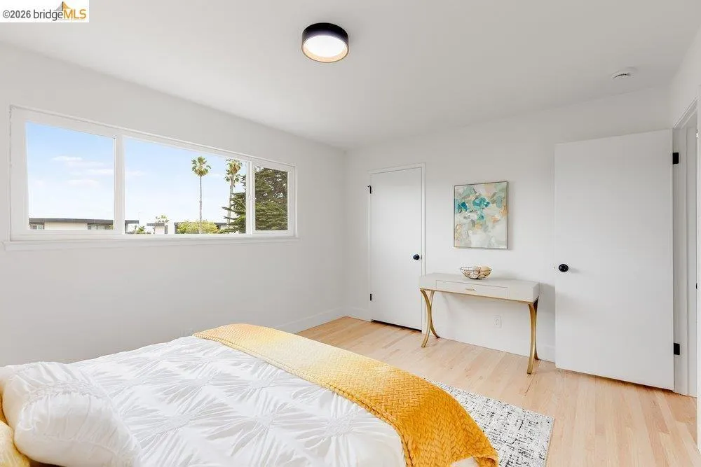 Bedroom featuring light wood-finish flooring, white walls, and a multi-pane window