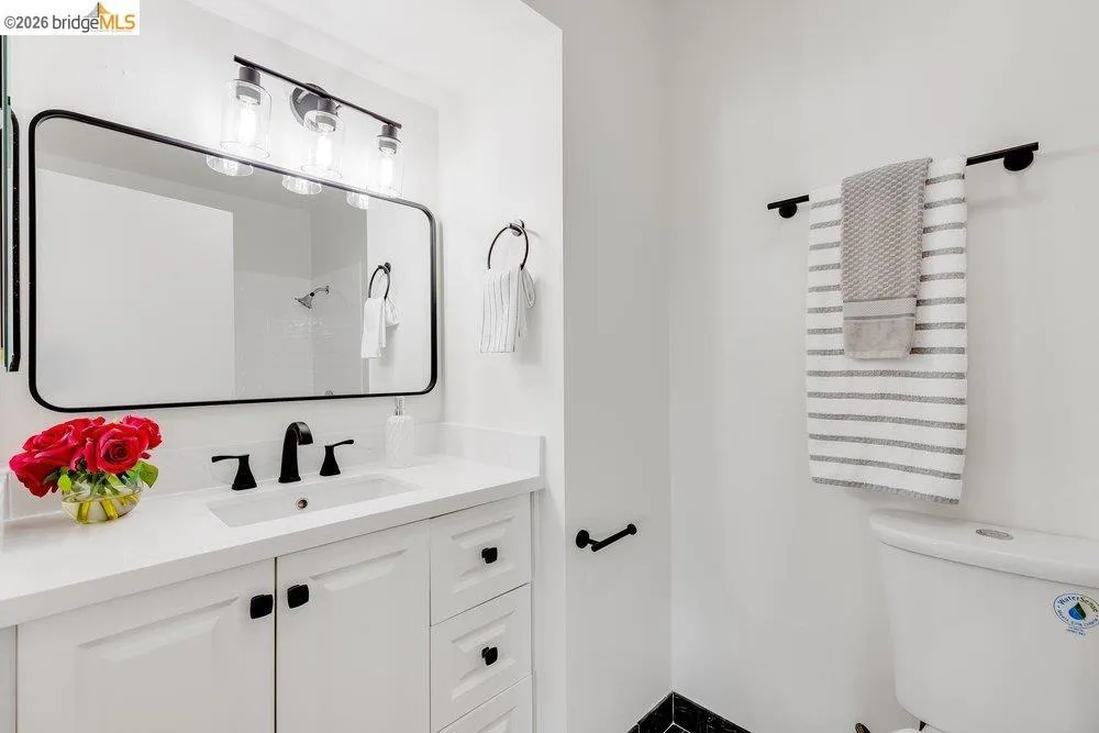 Bathroom vanity featuring a quartz countertop, integrated sink, and white cabinetry with matte black hardware