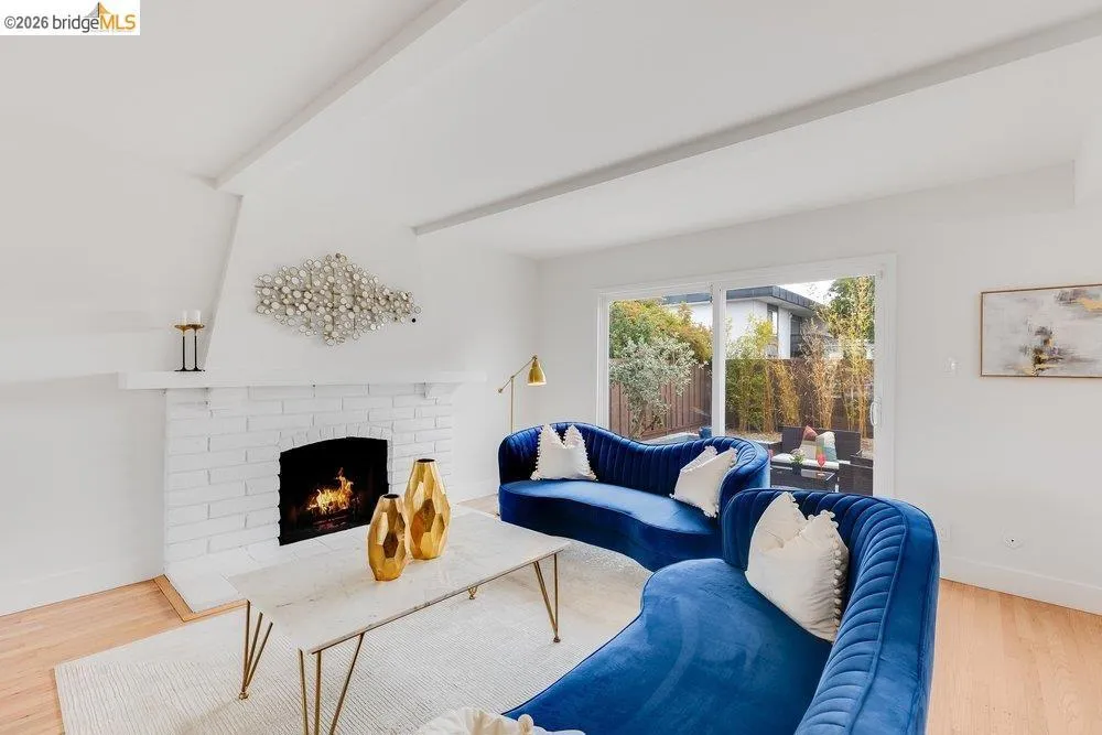 Living area featuring a white brick fireplace with a black firebox, light wood-finish flooring, and white walls