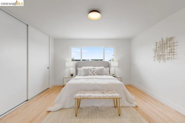 Light-filled room featuring a rectangular window, light wood-finish flooring, white walls, and a ceiling-mounted light fixture