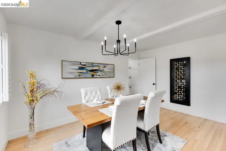 Dining area featuring a modern black chandelier, white ceiling beams, and wood-finish flooring