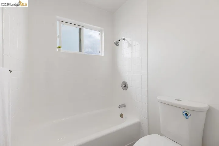 White-tiled bath and shower combination with a sliding window