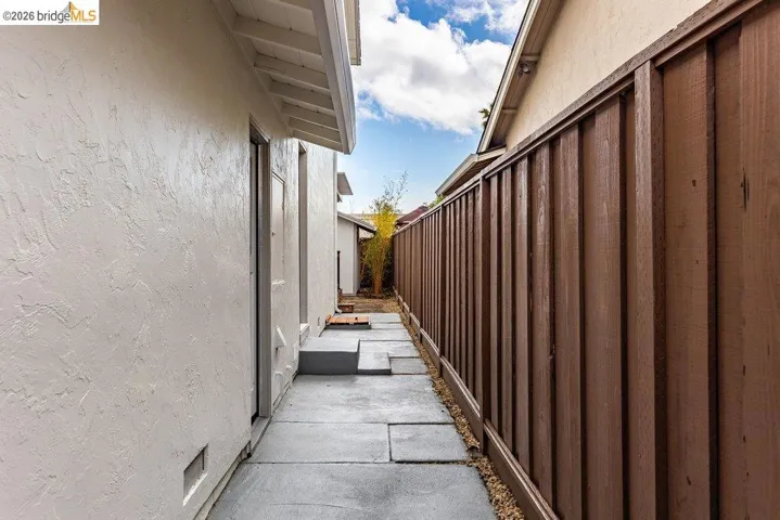 Side yard walkway featuring concrete pavers, gravel accents, and a wood privacy fence