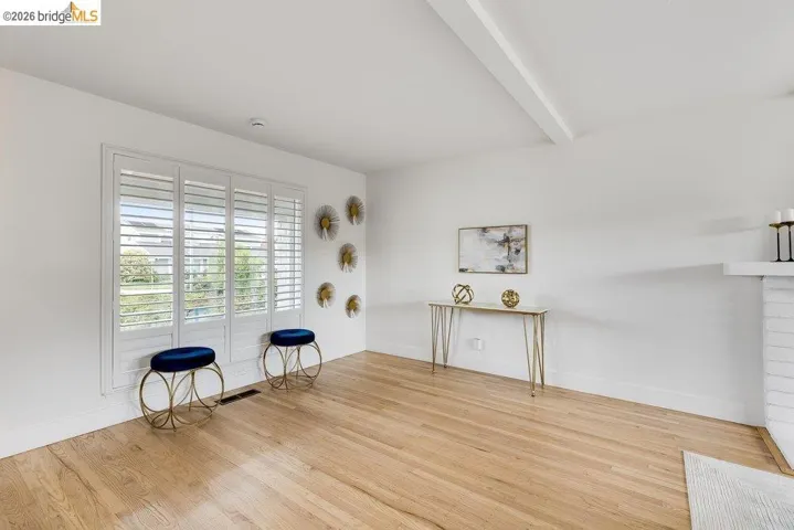 Hardwood flooring complements the bright white walls and ceiling beam