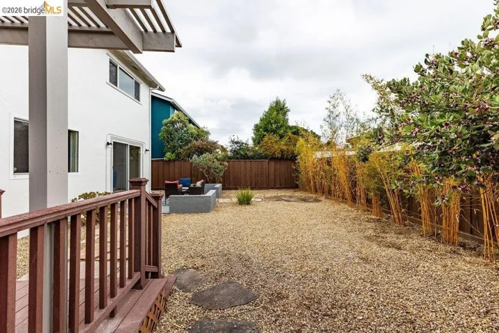Gravel-covered backyard featuring a built-in patio seating area with a decorative privacy wall