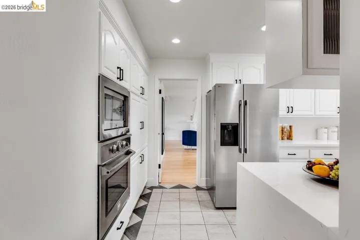 Kitchen featuring white cabinetry, stainless steel appliances, recessed lighting, and a patterned tile floor