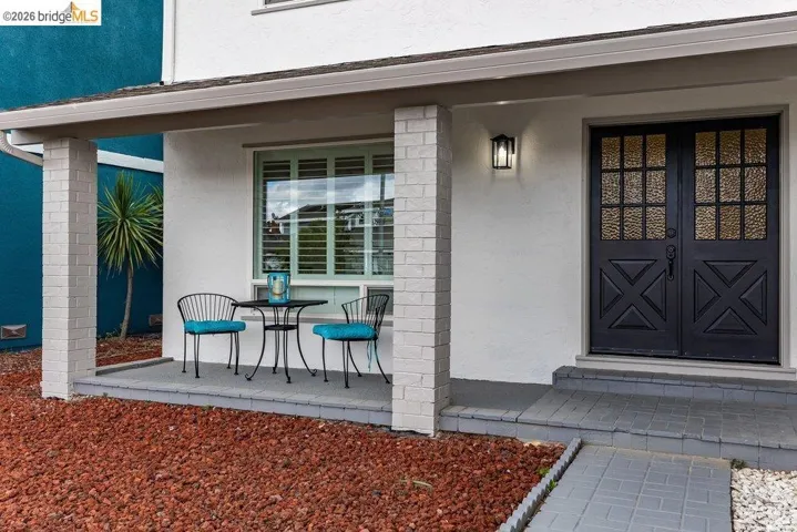 Covered front porch featuring brick columns and a paver walkway