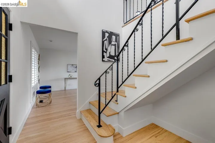 Hardwood flooring and a staircase with an ornamental wrought iron railing define this entryway