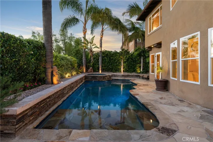 Resort-style backyard featuring a custom pool and spa, mature landscaping, and multiple areas for outdoor relaxation