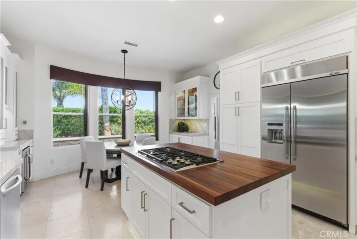 Remodeled kitchen featuring custom cabinetry, Taj Mahal quartzite countertops, stainless steel appliances, and a center island with butcher block countertop