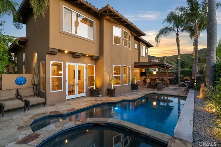 Resort-style backyard featuring a custom pool and spa, mature landscaping, and multiple areas for outdoor relaxation