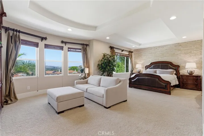 Spacious primary suite with a private sitting area, abundant natural light, and picturesque hillside and neighborhood views