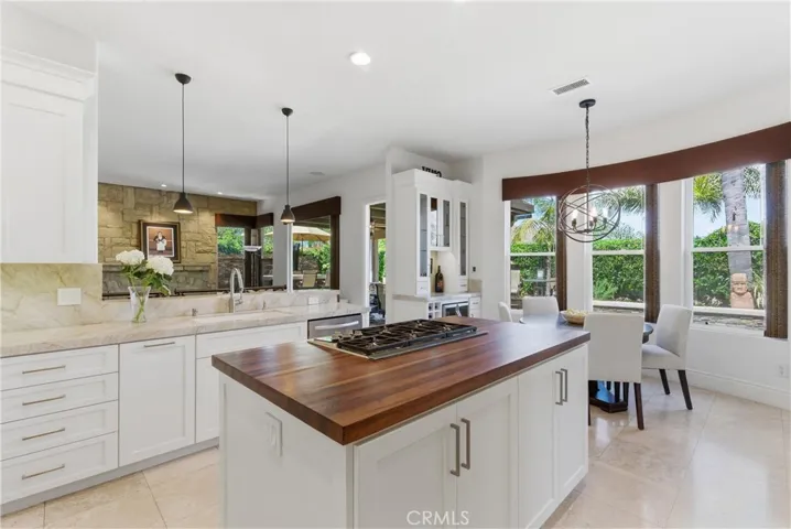 Remodeled kitchen featuring custom cabinetry, Taj Mahal quartzite countertops, stainless steel appliances, and a center island with butcher block countertop