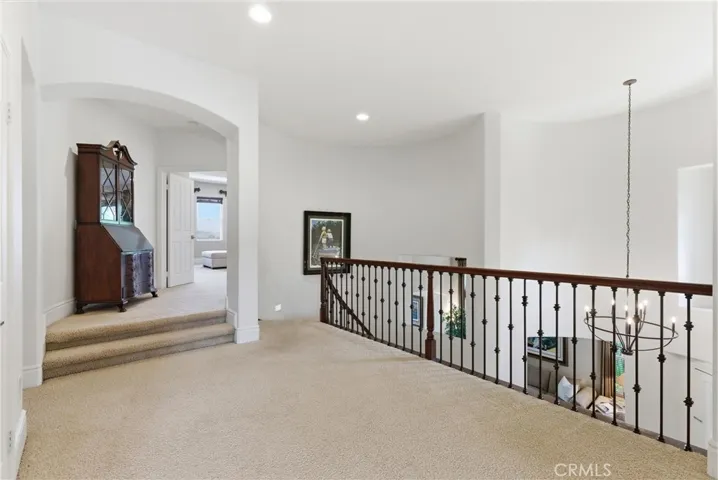pacious upper-level landing featuring wrought iron staircase accents