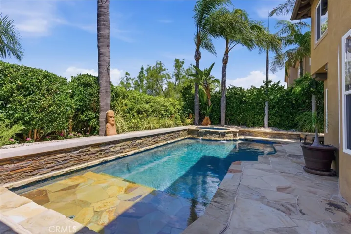 Resort-style backyard featuring a custom pool and spa, mature landscaping, and multiple areas for outdoor relaxation