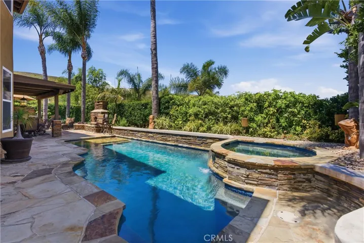 Resort-style backyard featuring a custom pool and spa, mature landscaping, and multiple areas for outdoor relaxation