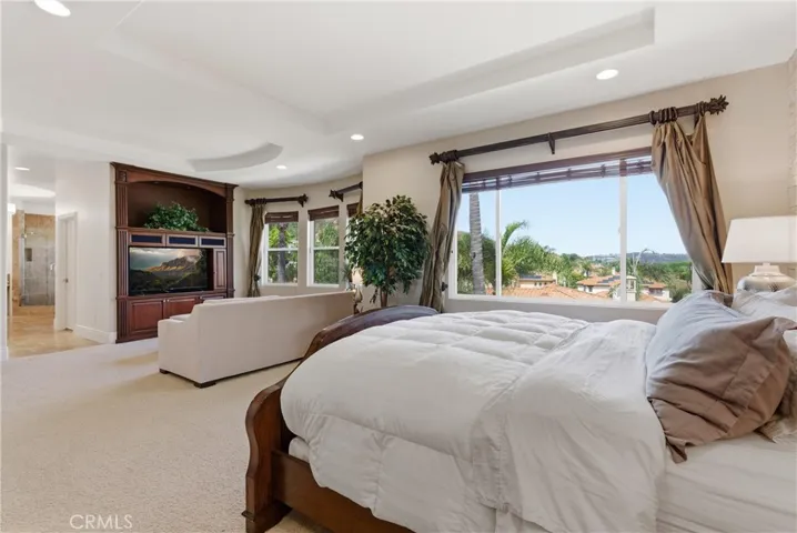 Spacious primary suite with a private sitting area, abundant natural light, and picturesque hillside and neighborhood views