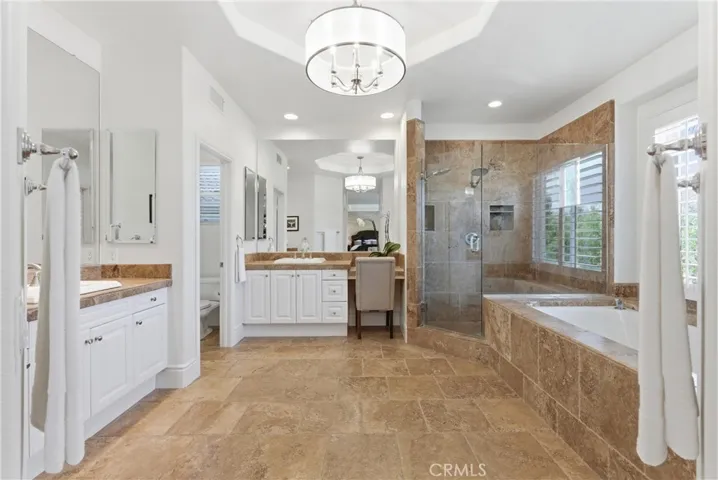 Spa-inspired primary bathroom with dual vanities, a soaking tub, and oversized walk-in shower