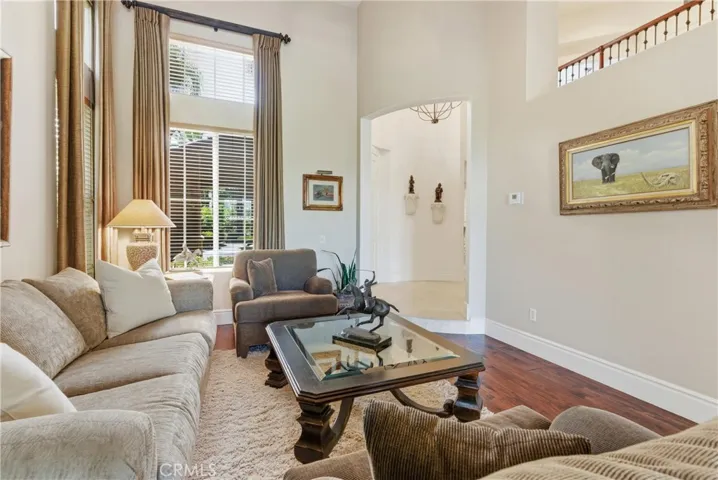 Light-filled living area with soaring ceilings, expansive windows, and rich wood flooring creating an inviting atmosphere