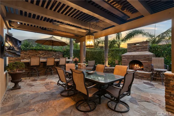 Covered outdoor entertaining area, a stone fireplace, and multiple seating spaces
