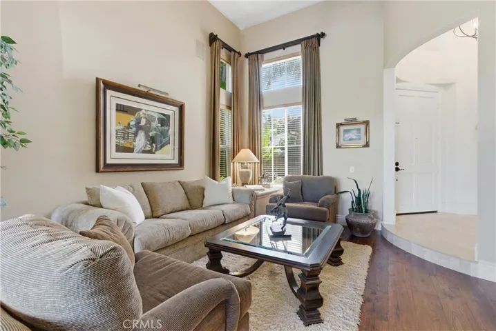 Light-filled living area with soaring ceilings, expansive windows, and rich wood flooring creating an inviting atmosphere