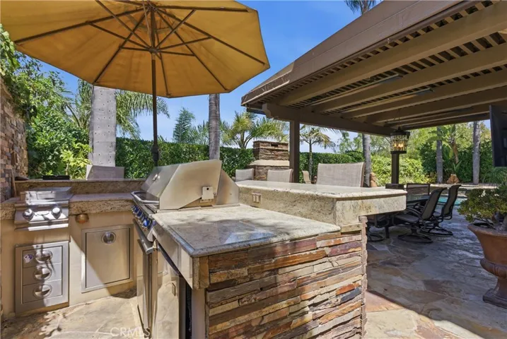 Private outdoor retreat with elevated bar seating, a built-in BBQ, lush tropical landscaping, and tranquil fountain accents