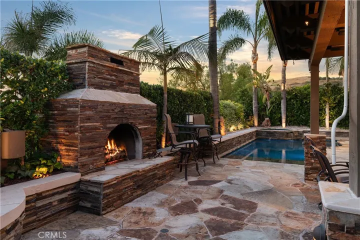Covered outdoor entertaining area, a stone fireplace, and multiple seating spaces