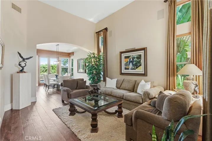 Light-filled living area with soaring ceilings, expansive windows, and rich wood flooring creating an inviting atmosphere