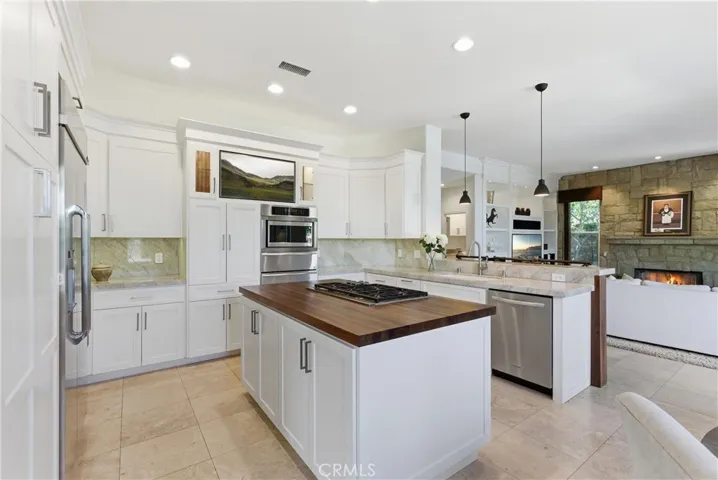 Remodeled kitchen featuring custom cabinetry, Taj Mahal quartzite countertops, stainless steel appliances, and a center island with butcher block countertop