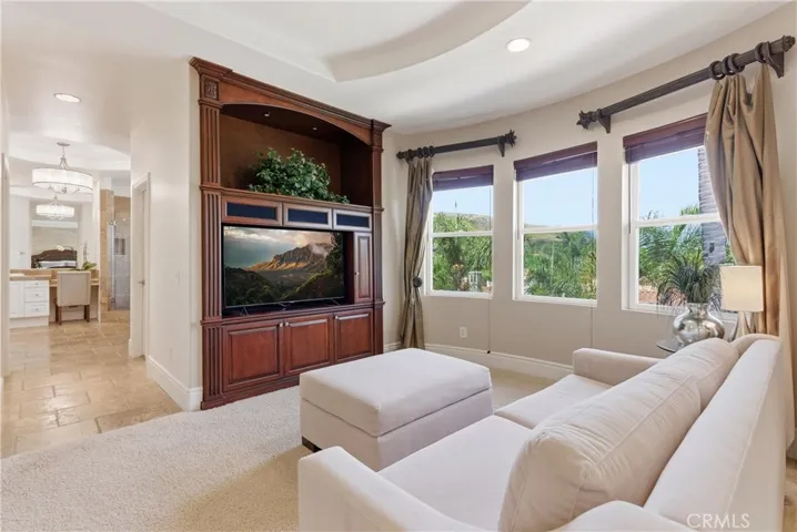 Spacious primary suite with a private sitting area, abundant natural light, and picturesque hillside and neighborhood views
