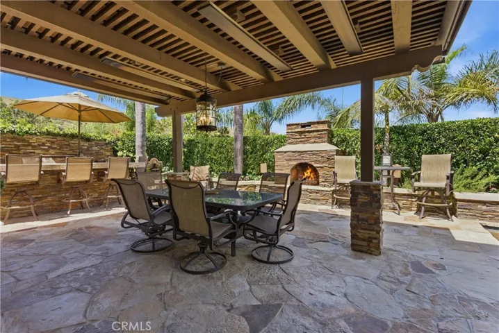 Covered outdoor entertaining area, a stone fireplace, and multiple seating spaces
