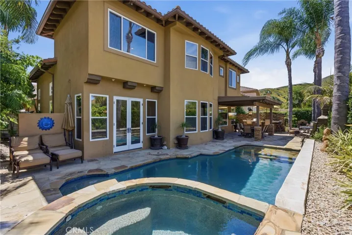 Resort-style backyard featuring a custom pool and spa, mature landscaping, and multiple areas for outdoor relaxation