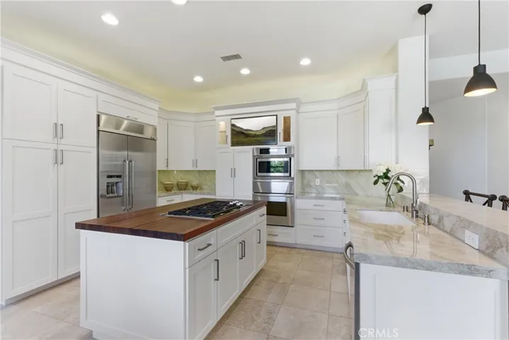 Remodeled kitchen featuring custom cabinetry, Taj Mahal quartzite countertops, stainless steel appliances, and a center island with butcher block countertop