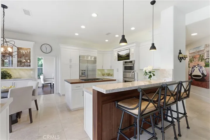 Remodeled kitchen featuring custom cabinetry, Taj Mahal quartzite countertops, stainless steel appliances, and a center island with butcher block countertop