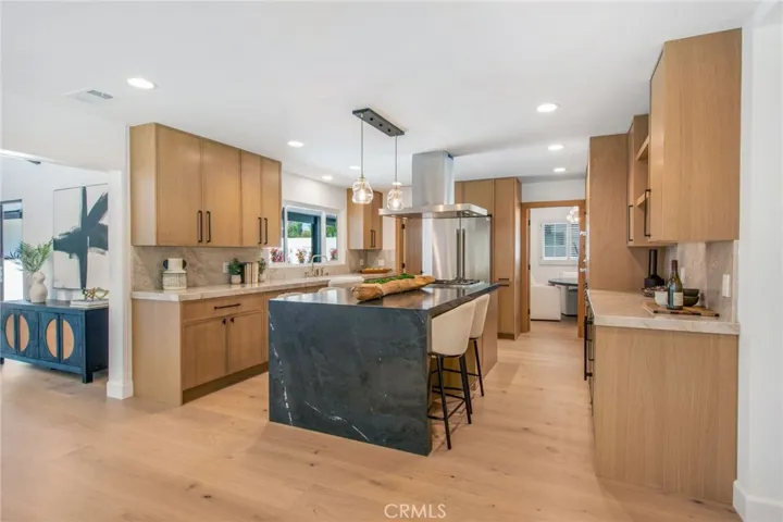 Chef's kitchen with Black Diamond quartzite waterfall island and rift-cut white oak cabinetry | 305 Robinhood Ln., Eastside Costa Mesa 92627