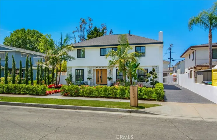 Stone-accented white stucco façade with manicured landscaping and mature palms | 305 Robinhood Ln., Eastside Costa Mesa 92627