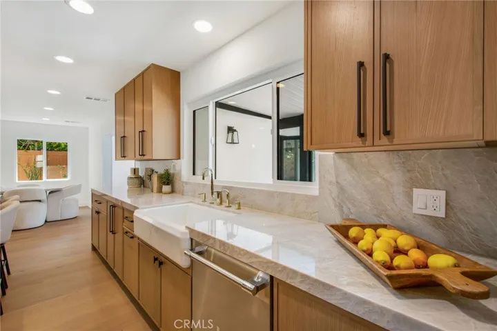 Taj Mahal quartzite perimeter counters with deep farmhouse sink and brass fixtures | 305 Robinhood Ln., Eastside Costa Mesa 92627