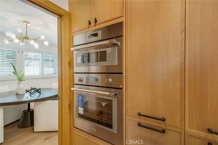 Stainless oven, microwave, and integrated refrigeration in custom rift-cut white oak cabinetry | 305 Robinhood Ln., Eastside Costa Mesa 92627